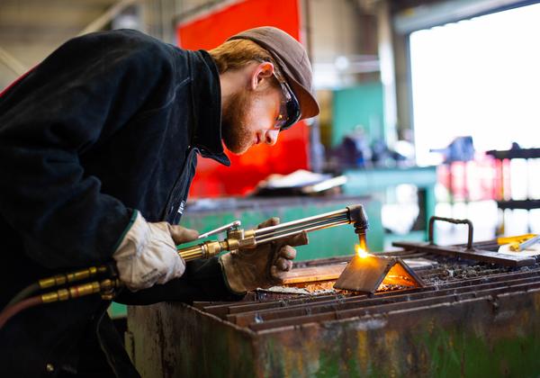 A VIU welding student wears safety classes, gloves and a hat while practicing their skills. 